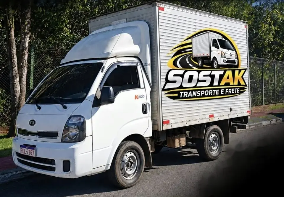 Caminhão baú branco da SOSTAK com o logotipo na lateral, estacionado